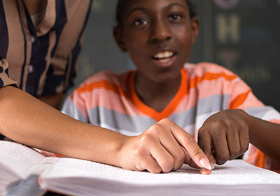 DeafBlind Central student reading from Braille book