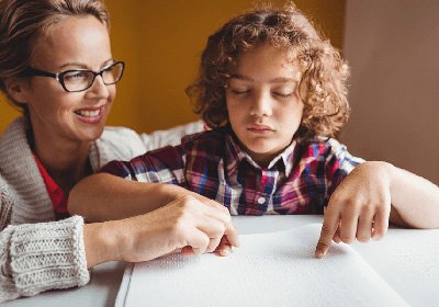 Adult and child read Braille book together