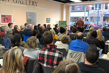 Eric Torgerson stands in front of a seated crowd to read from his poems during a Wellspring Literary Series event.