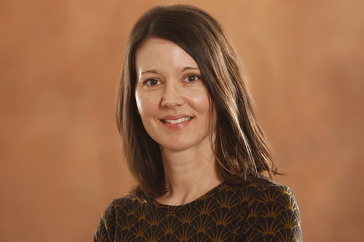 Closeup image of Carlin Borsheim-Black wearing a dark patterned shirt.