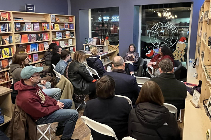 Guests seated in chairs inside a bookstore listen to two CMU faculty members leading a discussion.