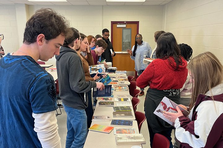 Michigan Poet Laureate Nandi Comer and Central Michigan University students line up along tables to view books by Michigan poets.