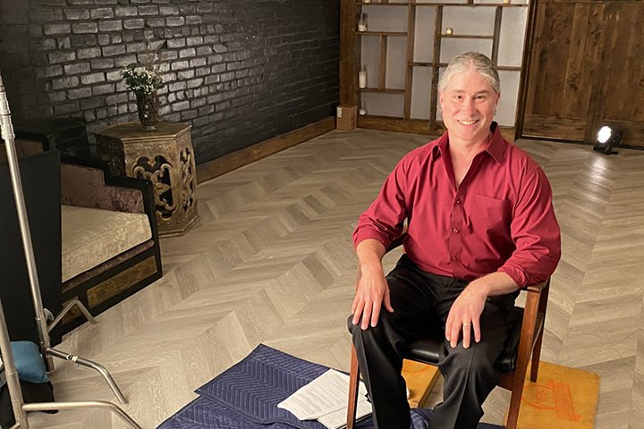 English professor Jeffrey Weinstock seated in a chair for an interview as part of a documentary on The Rocky Horror Picture Show.