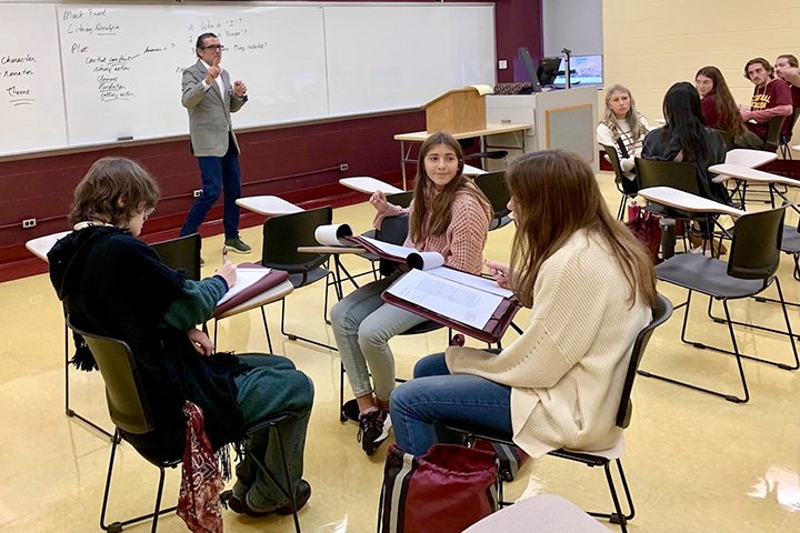 Professor Mark Freed stands at front of classroom with high school students seated at desks in small groups.