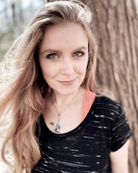 Closeup image of Kimberly Priest wearing a black shirt standing near a tree.