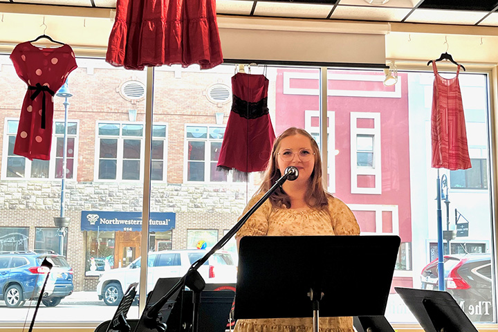 Mount Pleasant High School senior Bea Chapman reads her poetry while standing in front of a large glass window at Art Reach of Mid Michigan