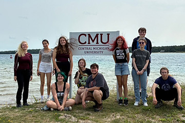 Students in Professor Robert Fanning’s English course, “Wonder and Wonder,” stand next to a Central Michigan University sign on Beaver Island.