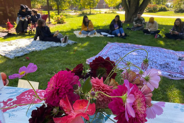 Flowers decorate a table while guests sit on blankets reading Walt Whitman's Leaves of Grass during an annual marathon reading.