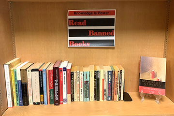 Image of a row of banned books on a shelf with a sign that says Knowledge is Power. Read Banned Books.