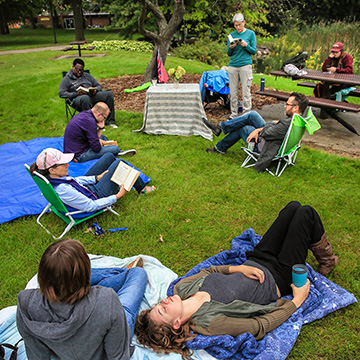 Individuals sit and lounge on blankets and chairs during the Walt Whitman Leaves of Grass marathon reading.