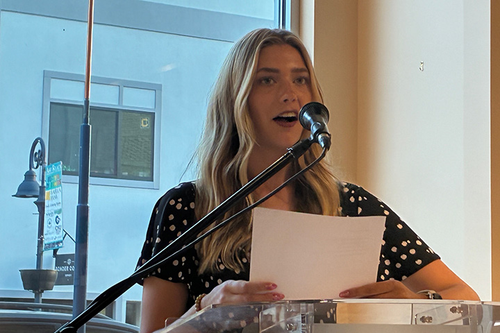 Autry Clark speaks into a microphone while holding a sheet of paper paper during the Wellspring Literary Series.