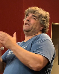 Poet Jeff Kass wearing a blue shirt and speaking in the Anspach 161 auditorium