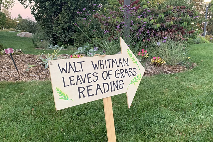 A wooden sign in the CMU Botanical Gardens with the words Walt Whitman Leaves of Grass Reading