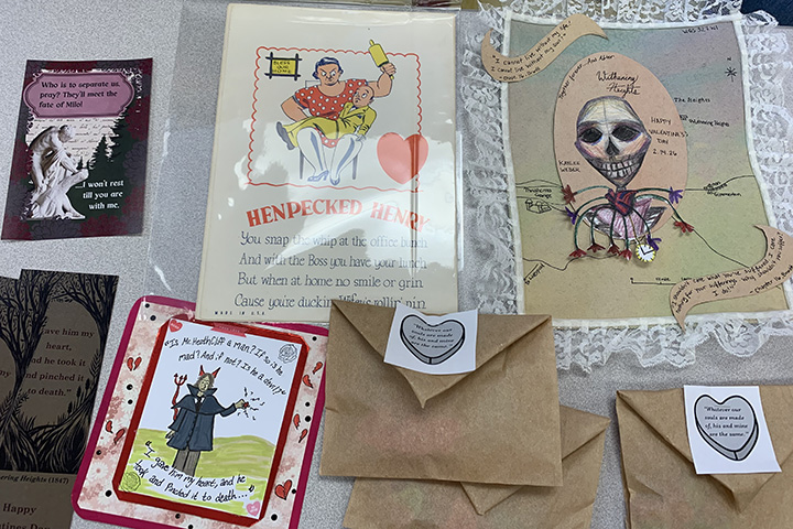 Student-designed bookmarks and envelopes are displayed on a desk.