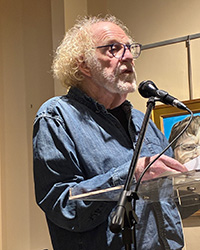 Jack Ridl reads his poetry while standing at a podium with a microphone