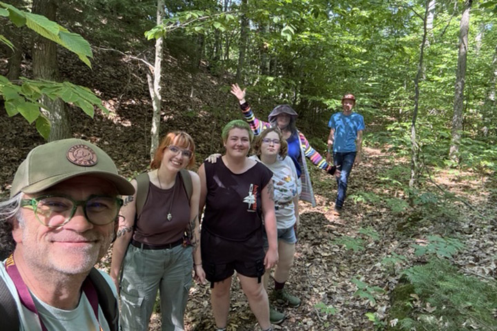 Professor Robert Fanning and students walk through a trail in the woods.