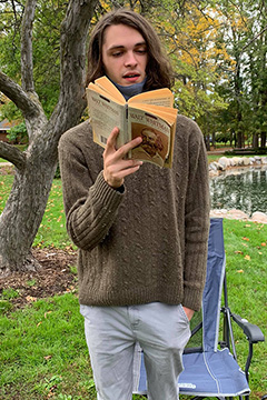 a student reading a book outside during the Walt Whitman Leaves of Grass marathon reading