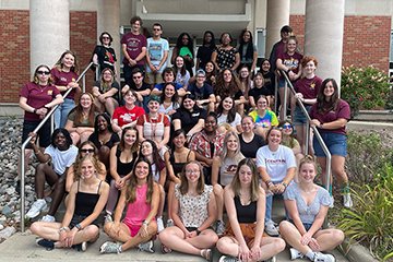 A large group of students from the Public Service Residential College sit and stand on the steps to Anspach Hall.