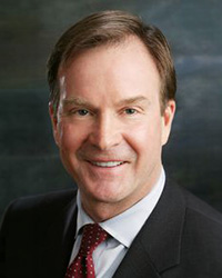 Closeup image of Former Michigan Attorney General Bill Schuette wearing a dark suit jacket and red tie.