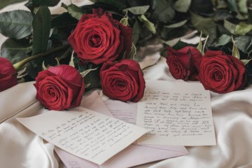 Image of red roses and handwritten letters on a light colored cloth