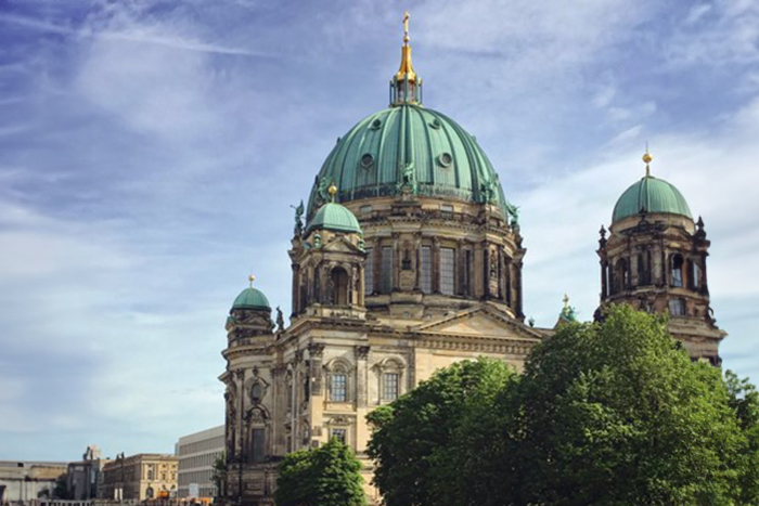 Image of the Bernliner Dom (Berlin Cathedral) with a large green dome and several smaller green domes on roof.