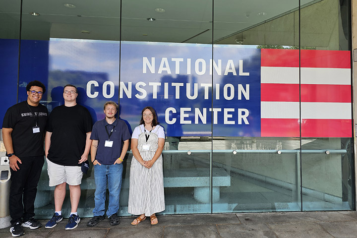 Four Social Studies Education students stand in front of the National Constitution Center sign