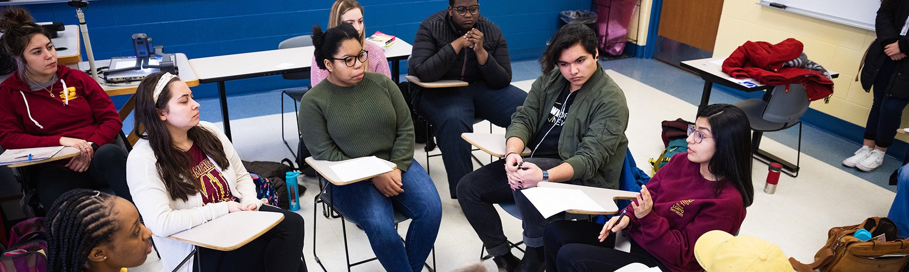 Dialogue Facilitators sit at desks facing each other inside a classroom