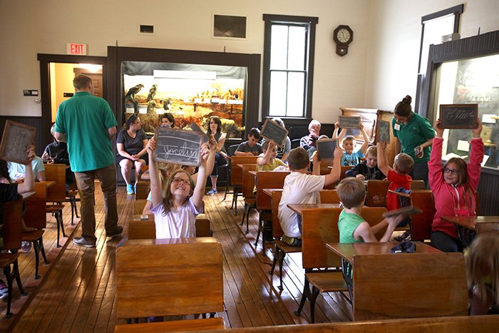 Elementary students participate in an educational activity at the one-room schoolhouse.
