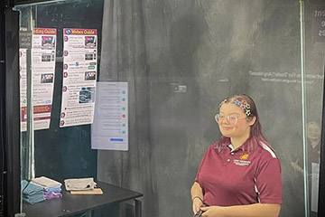 Image of Kayli Adams standing behind a lighted panel to give a virtual presentation in the CMU Lightboard Studio.