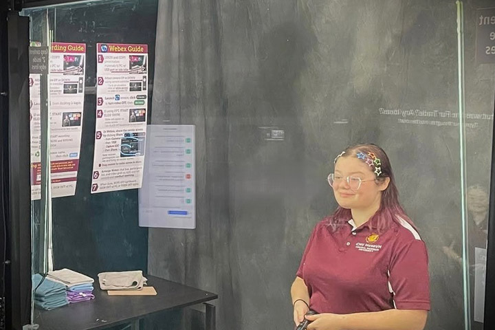 Image of Kayli Adams standing behind a lighted panel to give a virtual presentation in the CMU Lightboard Studio.