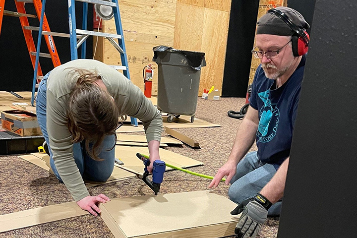 Ron Bloomfield and student with power tool and wooden boards and panels