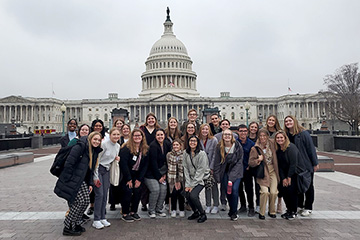 A group of Central Michigan University students and faculty member Emma Powell stand in front of the U.S. Capitol Building in Washington D.C.