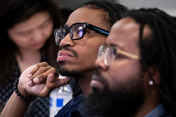 Two individuals seated next to each other and looking in the same direction