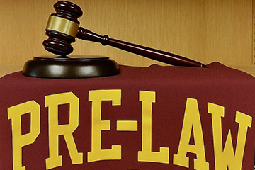 Image of a gavel on a maroon and gold Pre-Law table covering.