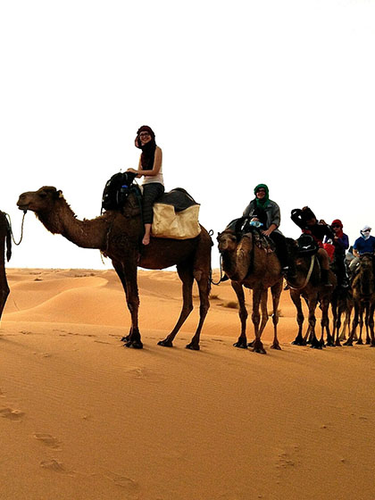 CMU student atop a camel in a desert