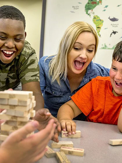 Two boys and school specialist playing Jenga