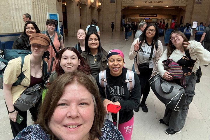 A group of individuals take a selfie together inside Union Station in Chicago with backpacks and luggage.