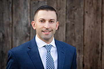 Professional photograph of Byron Nolde, keynote speaker for the Nolde Lecture Series, wearing a blue suit and tie