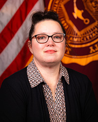 Closeup image of Lorie Olson wearing a black suit jacket and patterned shirt.