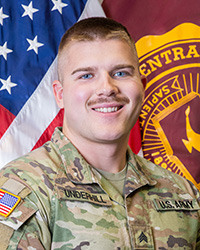 20250503_SGT_Trevor_Underhill_200x250 Closeup image of SGT Trevor Underhill wearing his military uniform with the American and Central Michigan University flags behind him.