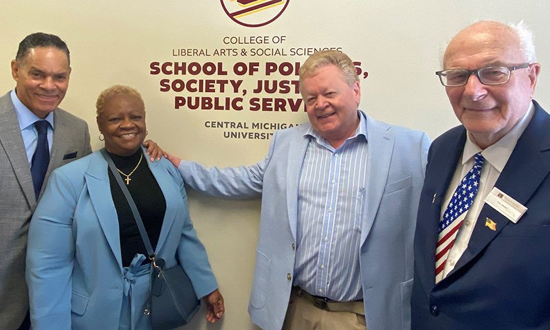 Leon Douglas, Gloria Douglas, David Kinney and Judge Fred Mester stand together in the office for the School of Politics, Society, Justice and Public Service.