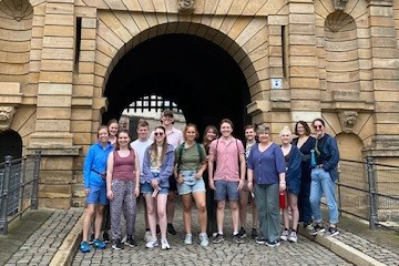 CMU students stand in two rows in front of a brick arch at the Petersberg Citadel in Erfut, Germany.