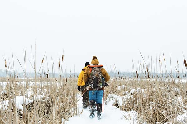 Students trekking through snowy Great Lakes wetlands.