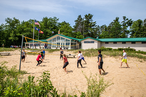 Students playing volleyball on a beach