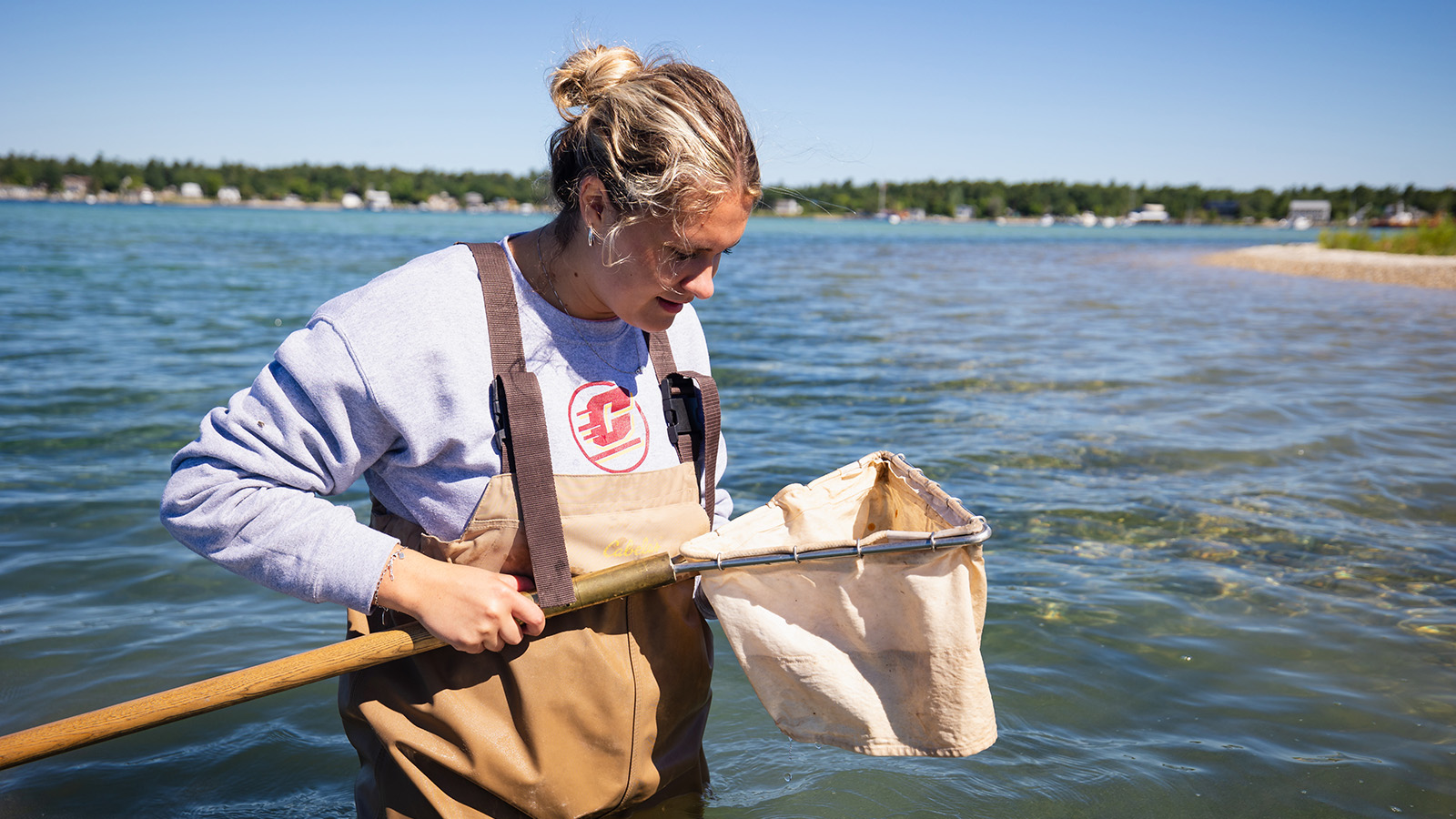 A woman standing in water holding a net.