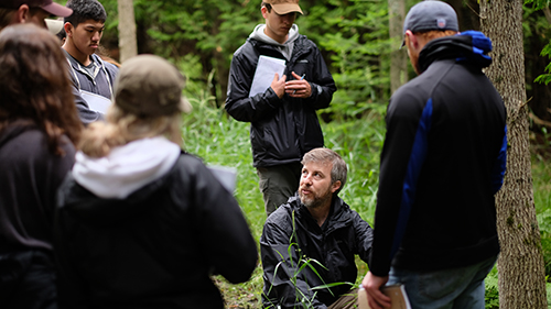 A CMU biology faculty member holding class in the woods at the CMU Biological Station on Beaver Island.