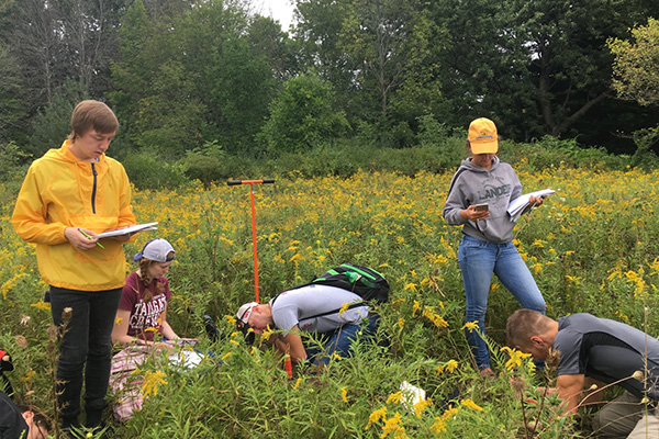A group of Environmental Science students taking and recording samples in a field on Beaver Island.