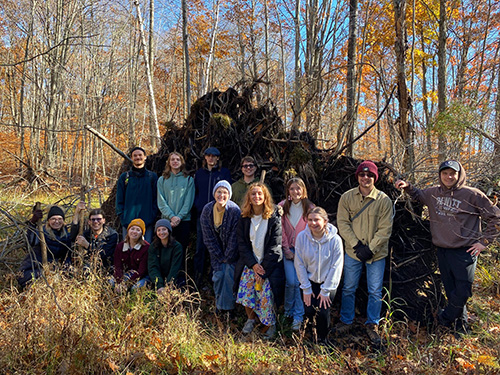 A group of visitors posing for a photo in front of a downed tree.