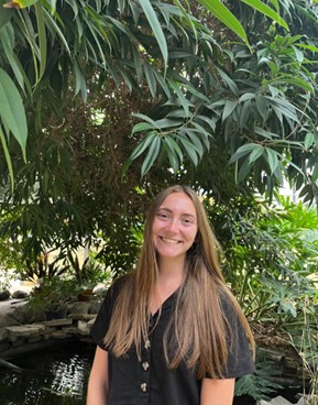 Lauren Dey in a dark shirt in front of a tree