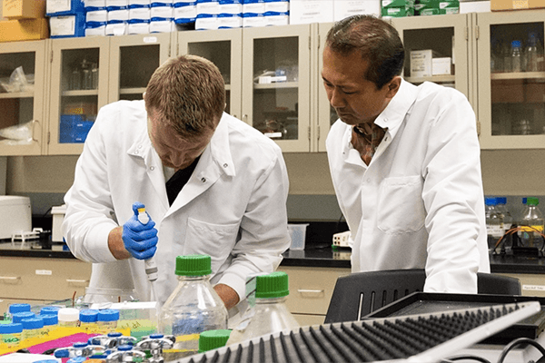 Ph.D. student and faculty member conducting sampling in the lab.